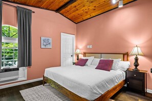 Un dormitorio con estructura de cama de madera, colcha blanca y dos lámparas de noche.