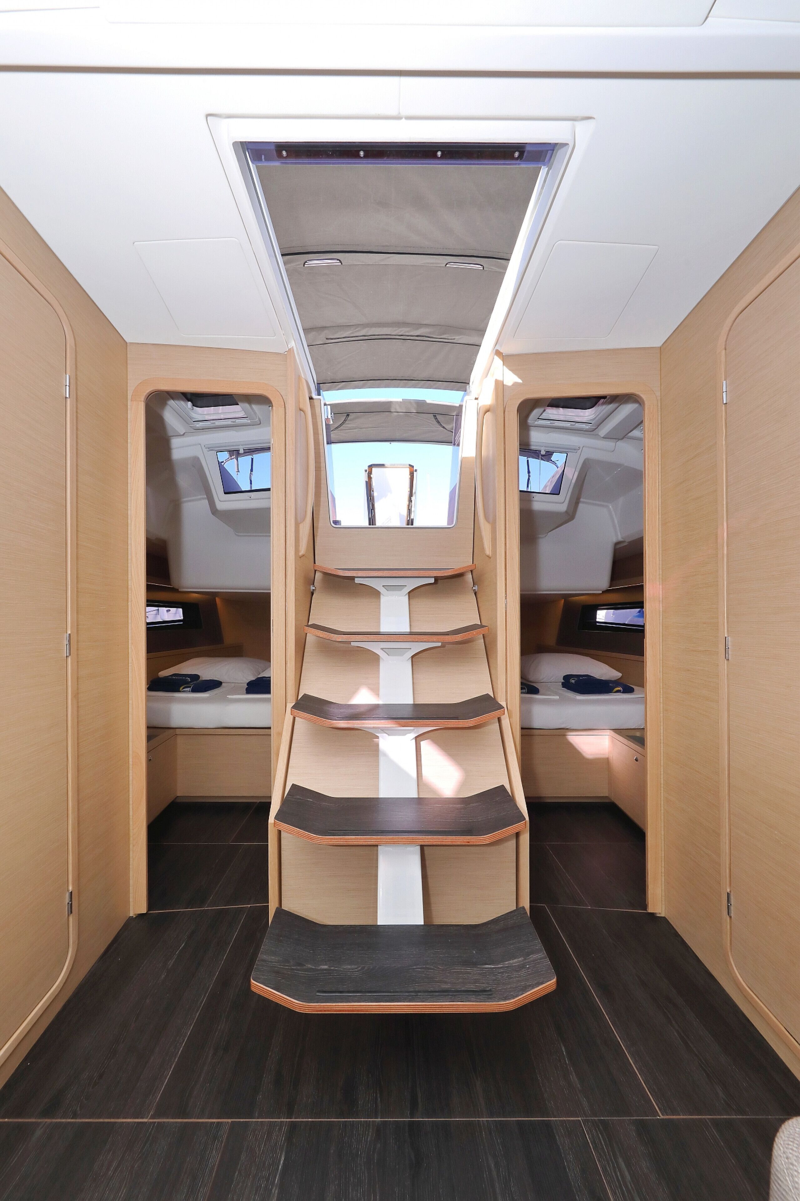 A compact, well-lit interior with a central seating area, built-in TV screens, and a dark wooden floor.