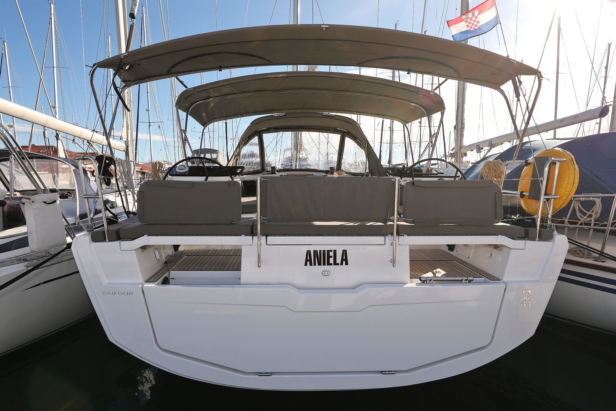 Ein Boot mit dem Namen 'ANIELA', ausgestattet mit einer geschützten Sitzgelegenheit, einem Steuer und dem Schriftzug 'DUFOUR'.