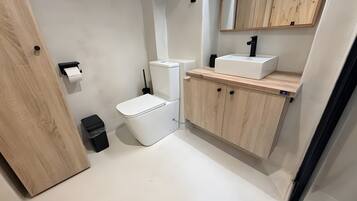 Un bagno piccolo con il water, un lavandino e mobiletti in legno.