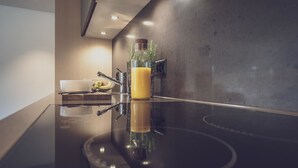 Una cocina moderna con una encimera reflectante, un tazón, una botella y una planta.