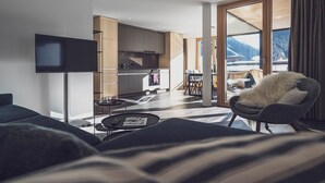 Una sala de estar moderna con un televisor de pantalla plana, un sofá, una mesa de centro y vistas a una cocina y comedor.