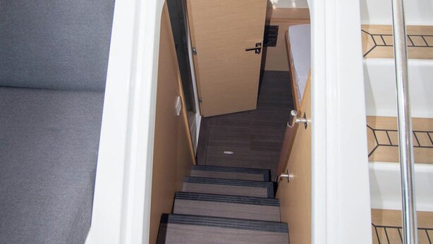A staircase with wooden steps and a metal handrail, leading to a room with a door and a small window.