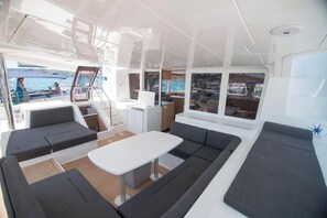 A yacht interior with a dining area, seating, and a view of the water. - Sun-Kissed Sailing Adventure in Islas Baleares, Mallorca (Palma)