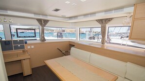 A cabin with a bed, a desk, and a window with a view of the marina.
