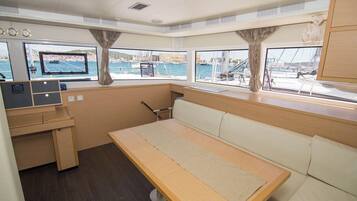 A cabin with a bed, a desk, and a window with a view of the marina.