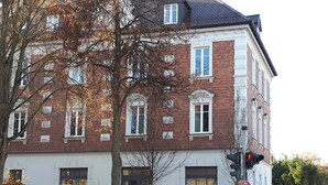 Ein mehrgeschossiges Gebäude mit Backsteinfassade, großen Fenstern und einem gut sichtbaren Eingang.