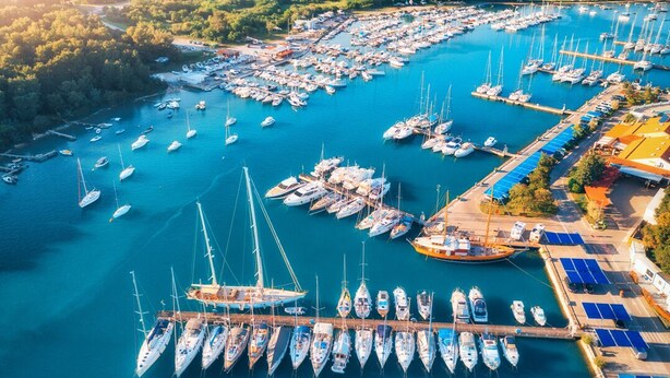 An aerial view of a marina with numerous boats docked, surrounded by greenery and buildings. - Sun-Kissed Sailing Adventure in Istria, Croatia (Pula)