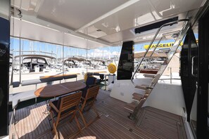 A boat deck with a table and chairs, a steering wheel, and a view of other boats. - Sun-Kissed Sailing Adventure in Zadar, Croatia (Bibinje)