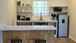 Una cucina moderna con isola centrale, sgabelli da bar, frigorifero e una finestra con tende.