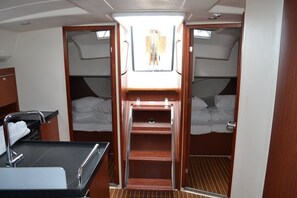 A compact interior with a kitchenette, two beds, a small bathroom, and a window. - Sun-Kissed Sailing Adventure in Zadar, Croatia (Bibinje)