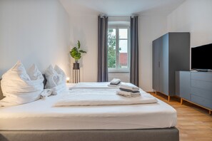 A hotel room with a large bed, a television, a wardrobe, and a window with curtains. - Stadt Land Fluss Apartment 5 (Regensburg)
