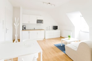 A modern, white interior with a kitchen, dining area, and living space.