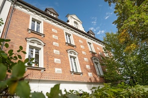 Ein Gebäude aus roten Ziegelsteinen mit weißer Fassade, mehreren Fenstern und einem sichtbaren Schornstein.