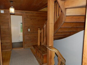 A wooden staircase with a bench, a door, and a light fixture. - Tree-Tops, Chalet Appartement/Fewo, Dusche und Bad, WC 9-Bettwohnung by Interhome (Gstaad)
