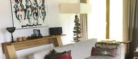 En stue med en sofa, en lampe, et billede og et vindue med gardiner.