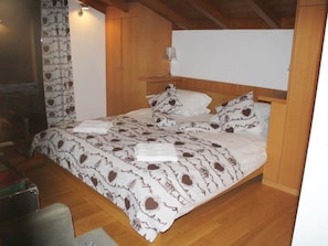 Un dormitorio con una cama de madera, una mesita de noche, una lámpara y una colcha estampada.