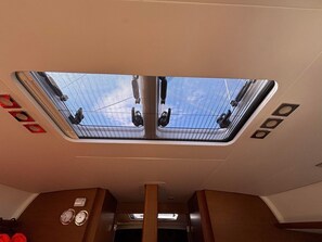 Ein Zuginnenraum mit Dachfenster, Gepäckablage und einem Fenster.