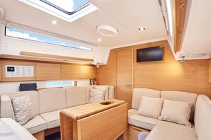 A modern interior with a sofa, a wooden table, a TV mounted on the wall, and a skylight.
