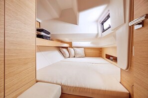 A compact interior with a bed, storage compartments, and a skylight.