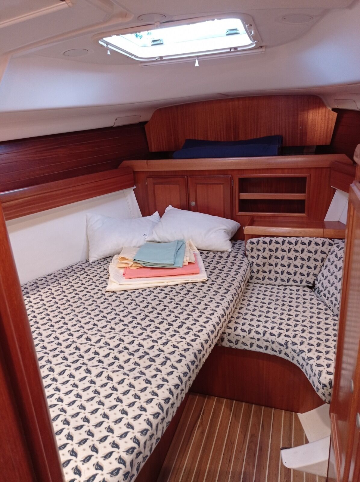 Ein kompaktes Kabinenzimmer mit zwei Betten, einer kleinen Sitzecke und einem Dachfenster.