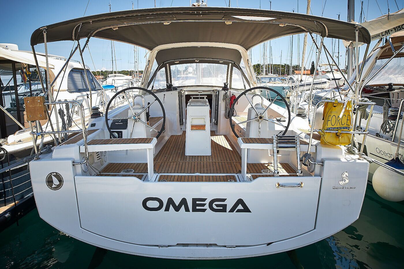 A boat with a white deck, a steering wheel, and the brand name 'OMEGA' on the bow.