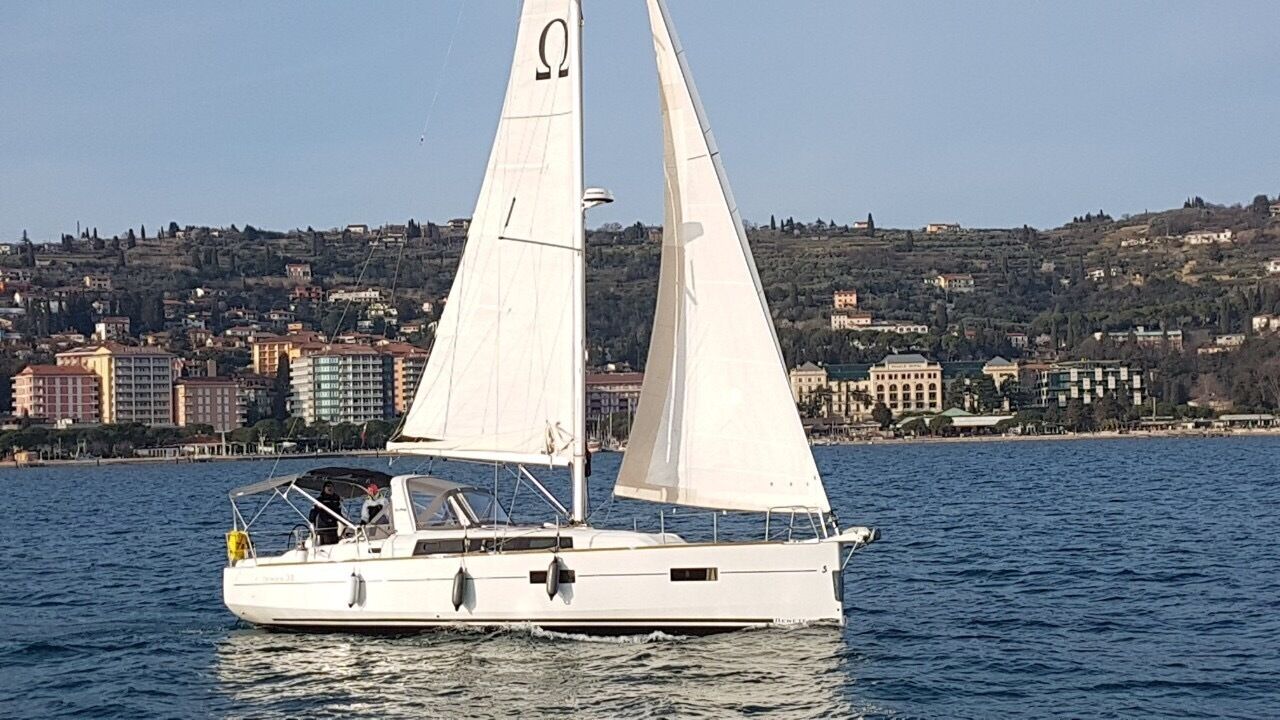 A sailboat on calm water with a cityscape in the background.