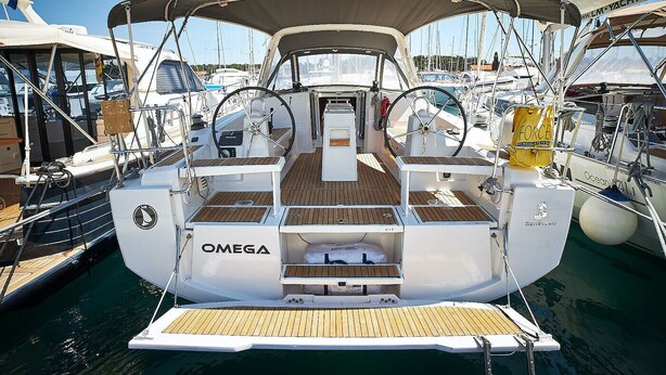 Eine Yacht mit überdachter Deckfläche, einem Omega-Logo und einem Wakeboard im Hintergrund.