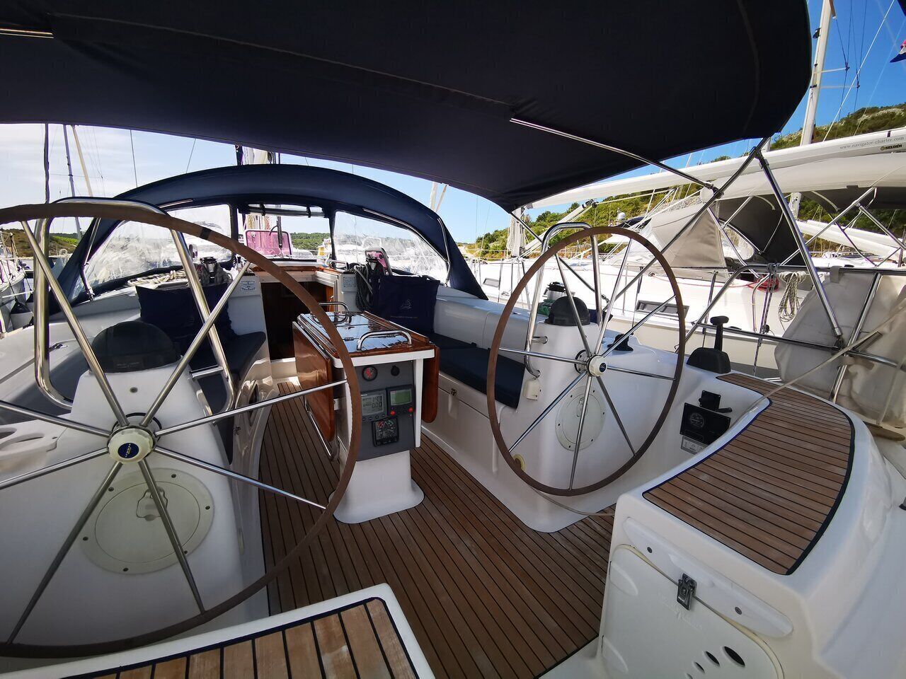A boat's deck with a steering wheel, control panel, and seating area.
