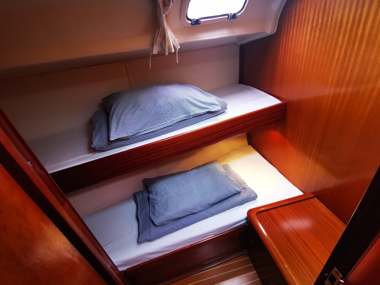 A compact cabin with two bunk beds, a small window, and a wooden interior.