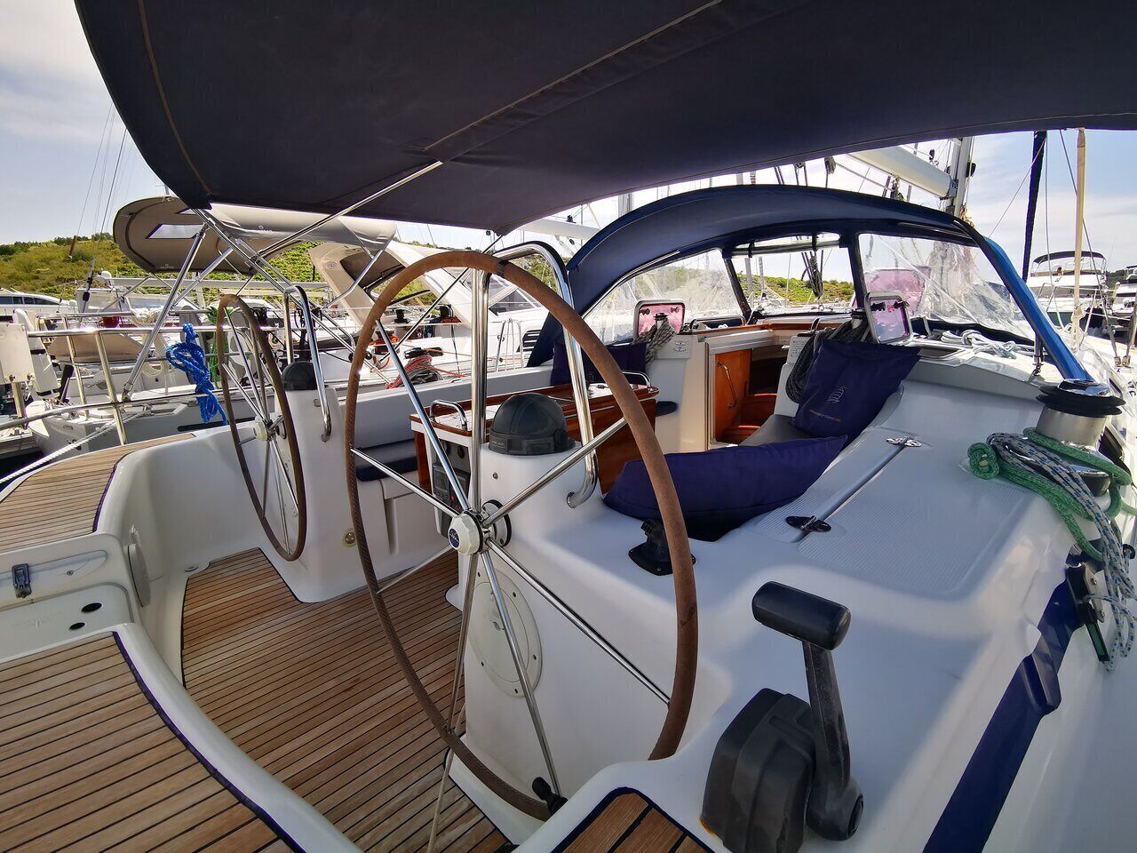 A sailboat's deck with a steering wheel, helm station, and seating area.