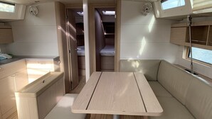 Een compact interieur met een centrale tafel, zitplaatsen en een smalle doorgang.