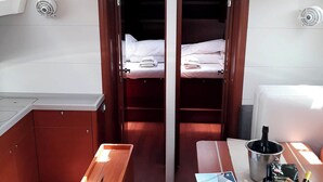 Una habitación compacta con dos camas, una kitchenette pequeña y una mesa con una botella y algunos snacks.