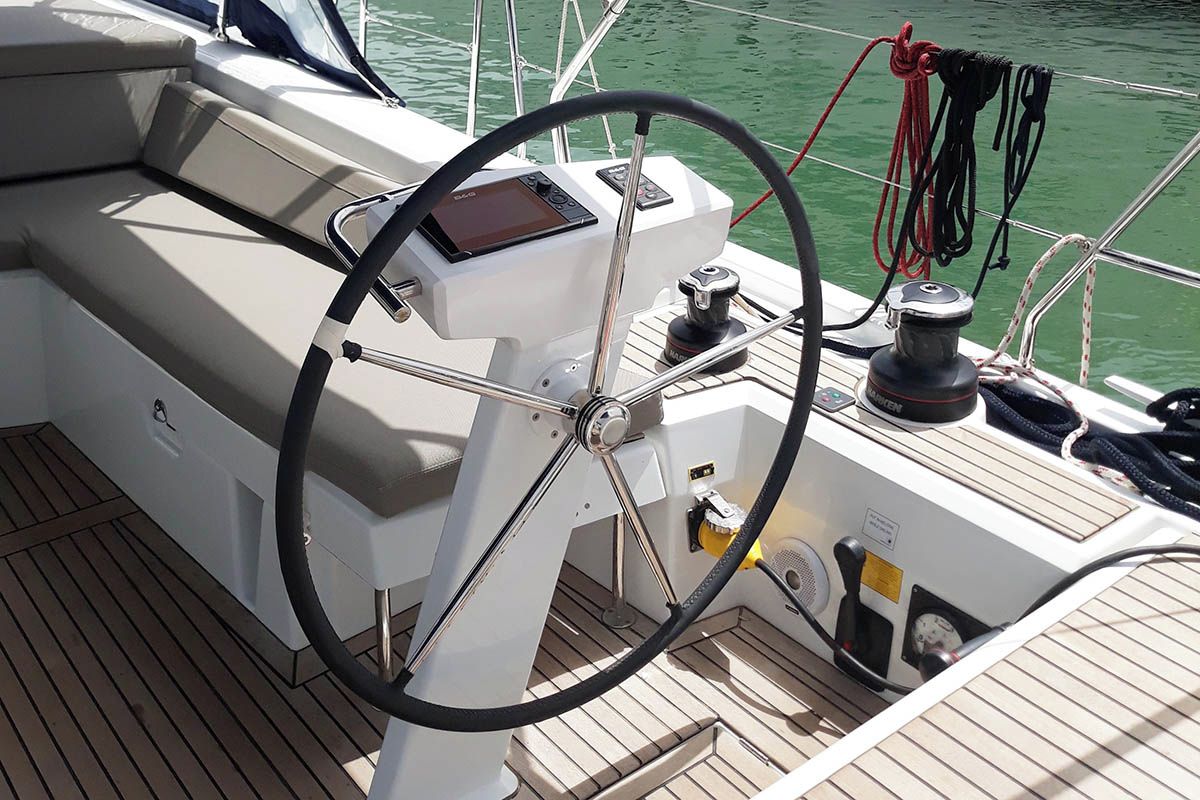 A boat's steering wheel, control panel, and deck.