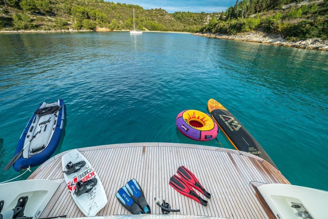 Un pont de bateau avec un canot pneumatique bleu, une planche de paddle blanche et un flotteur jaune.