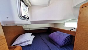 Un espacio para dormir compacto con cama, almohadas y ventana.