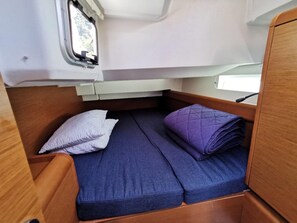 Een klein slaapgedeelte met een bed, kussens en een raam.