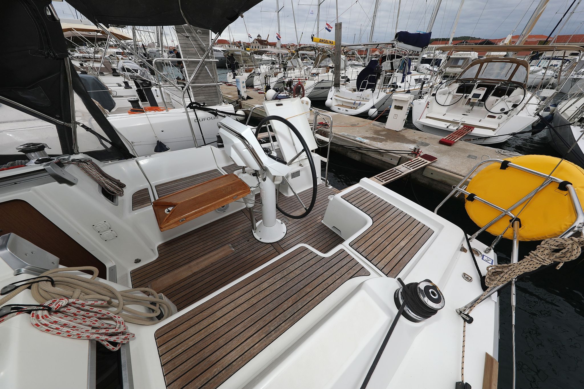 Een jachthaven met verschillende boten afgemeerd, een houten dek en een gele boei.
