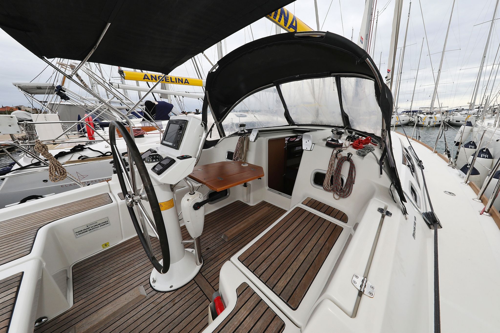 A boat deck with a steering wheel, control panel, and seating area.
