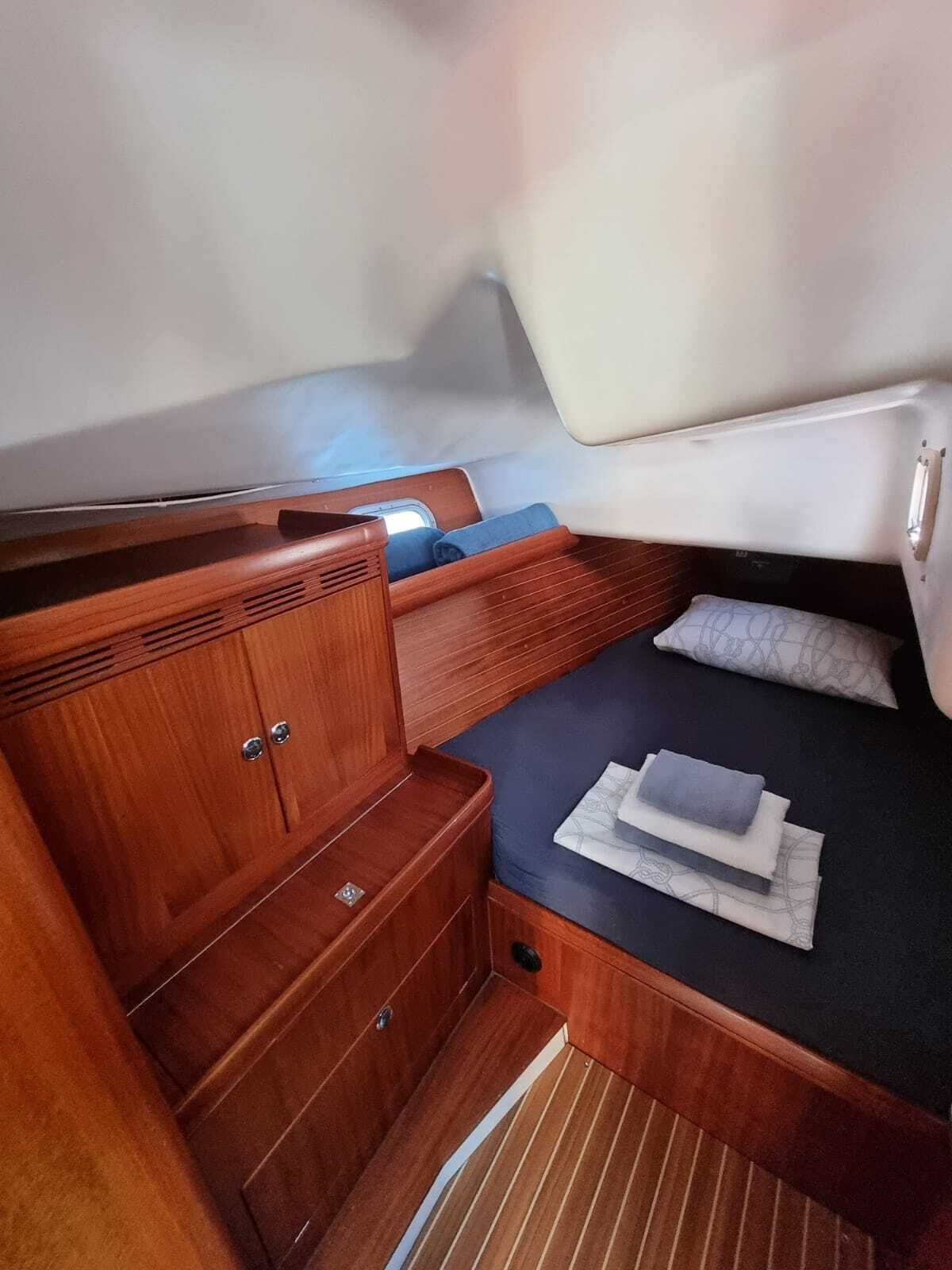 Une petite cabine comprenant un lit, une armoire en bois et un petit coin salon.