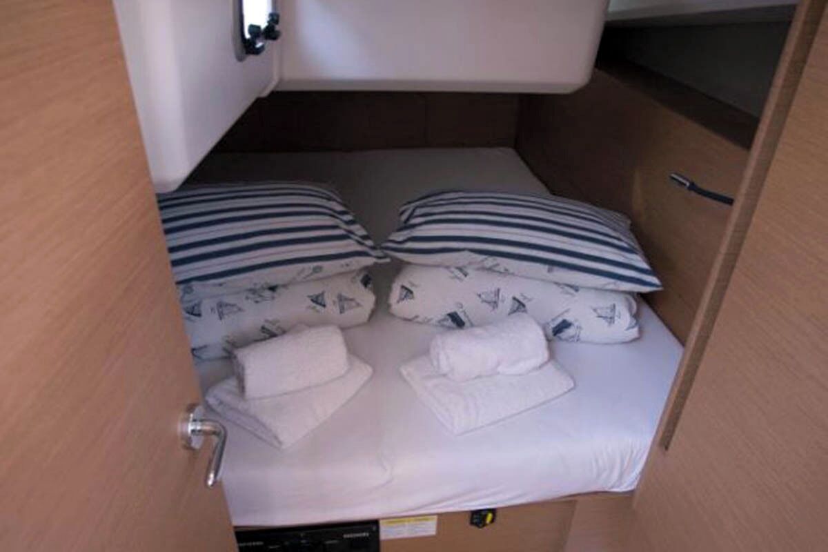 Habitación de hotel compacta con una cama individual, almohadas a rayas y toallas dobladas con cuidado.