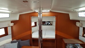 A cabin with a central bed, a small table, and a window. - Sun-Kissed Sailing Adventure in Zadar, Croatia (Biograd na moru)
