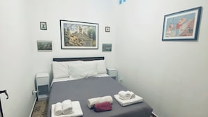 A hotel room with a bed, a ceiling fan, a nightstand, a wall clock, and a framed picture. - Blue Dream Balestrate (Balestrate)
