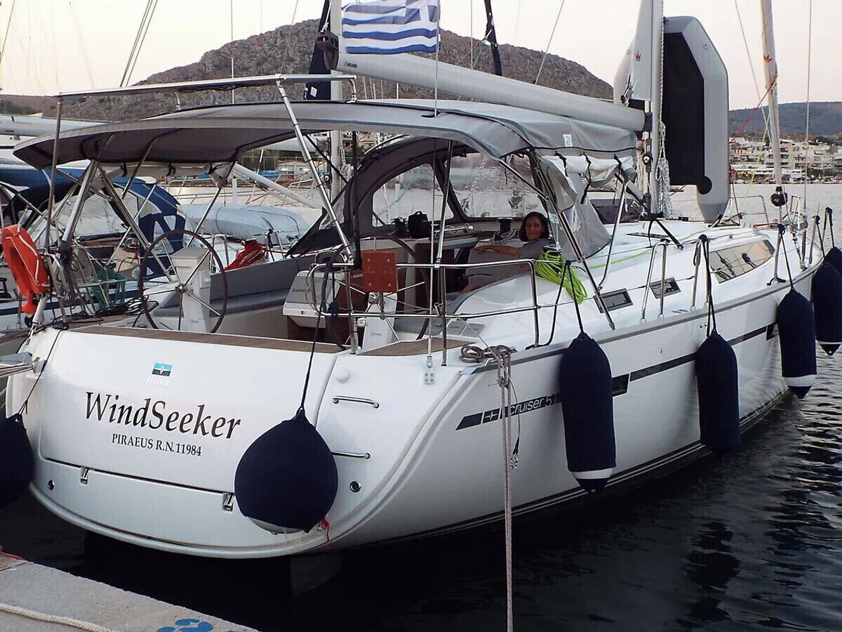 A white yacht named WindSeeker docked at a marina with a rocky landscape in the background.