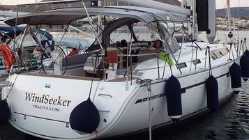 A white yacht named WindSeeker docked at a marina with a rocky landscape in the background.