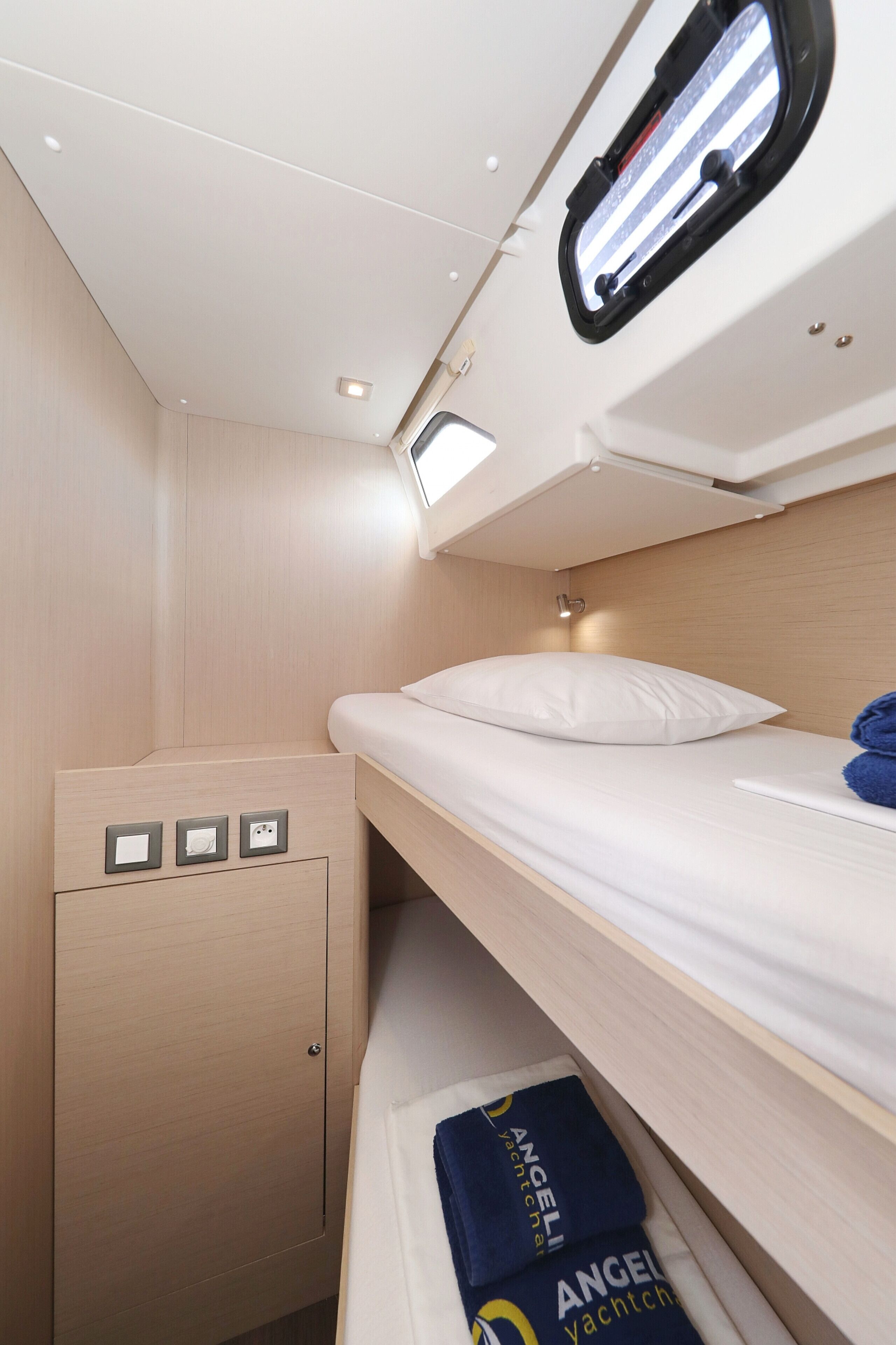 A bunk bed with a headboard, a small cabinet with a light, and a window with a view of the sky.