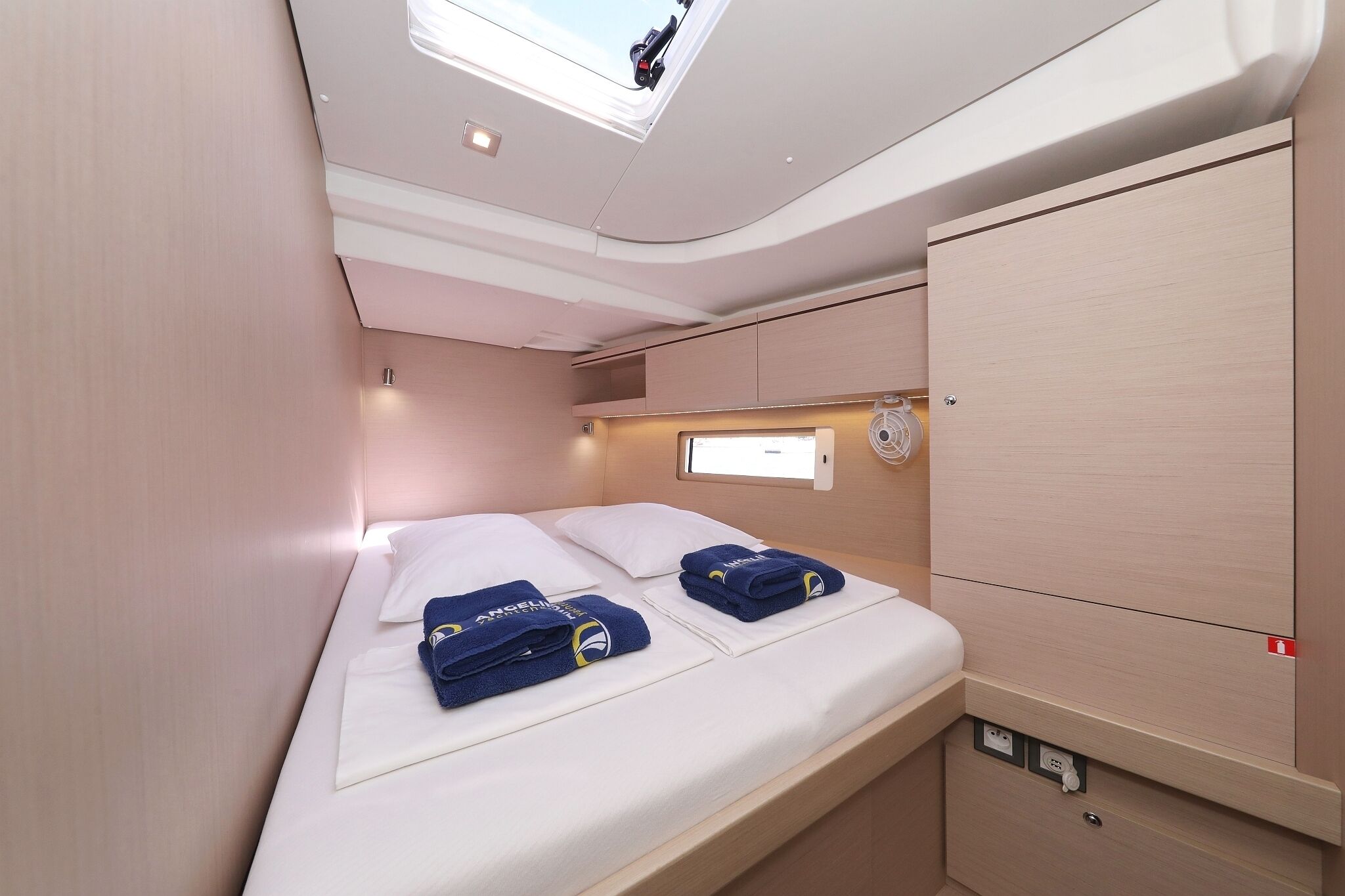 A compact, well-lit room with a bed, a small window, and a built-in cabinet.