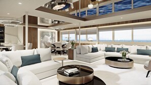 Un salon moderne comprenant un ensemble de canapés, une table basse et un coin repas avec vue sur la mer.