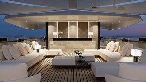 Un intérieur de yacht moderne avec un espace salon central, un bar et une vue sur l’océan.
