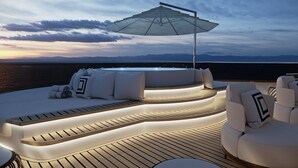 Un espace extérieur ensoleillé, aménagé avec un jacuzzi, des chaises longues et une terrasse en bois.